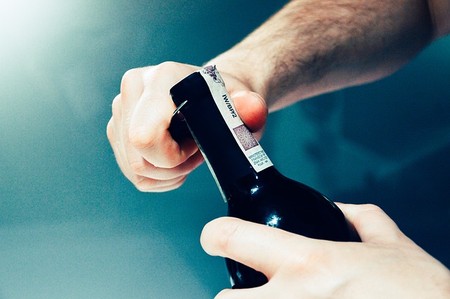 Detail mužských rukou otevírajících láhev vína